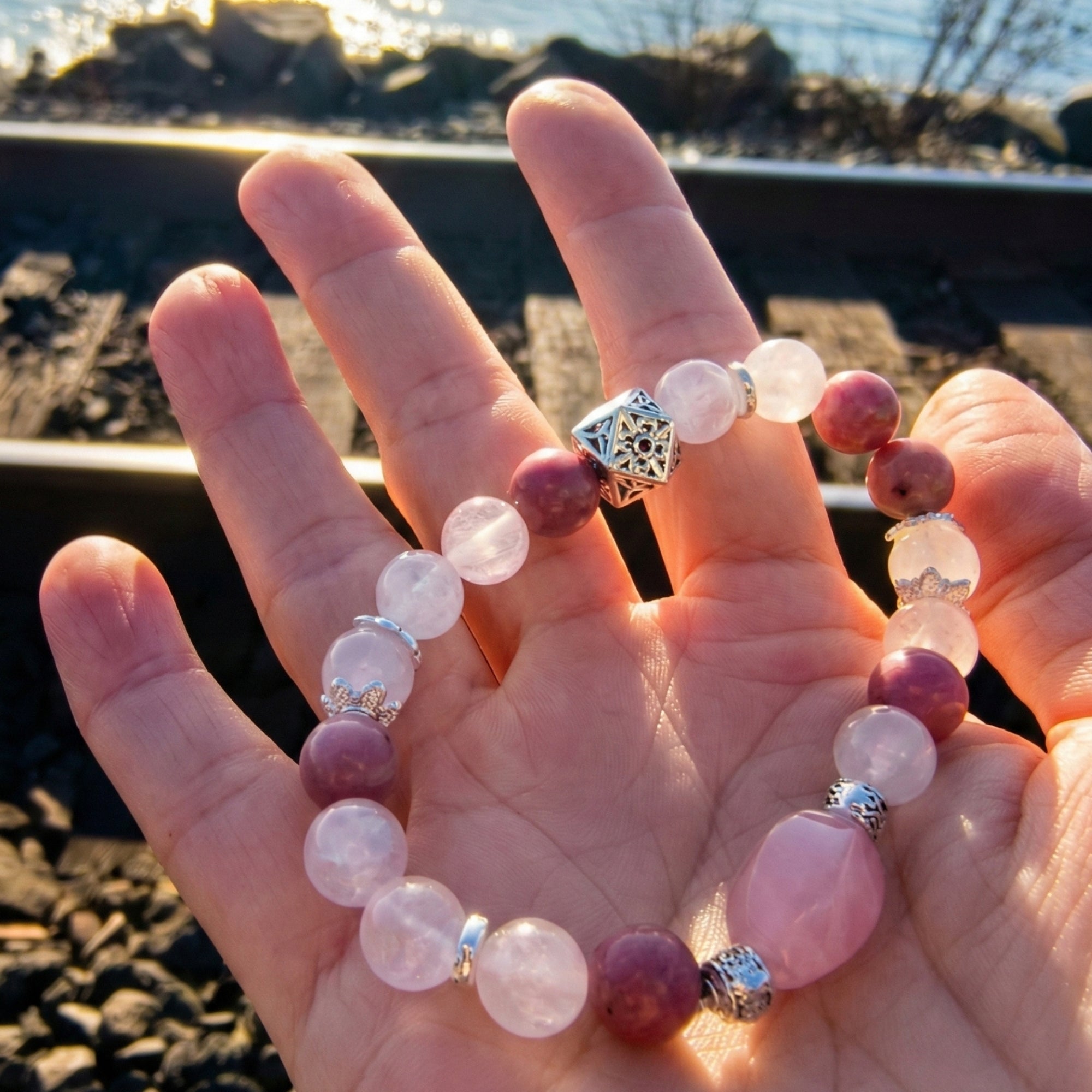 Amelis - love bracelet Rose Quartz White Quartz Rose Rhodonite holding on hand at outdoor