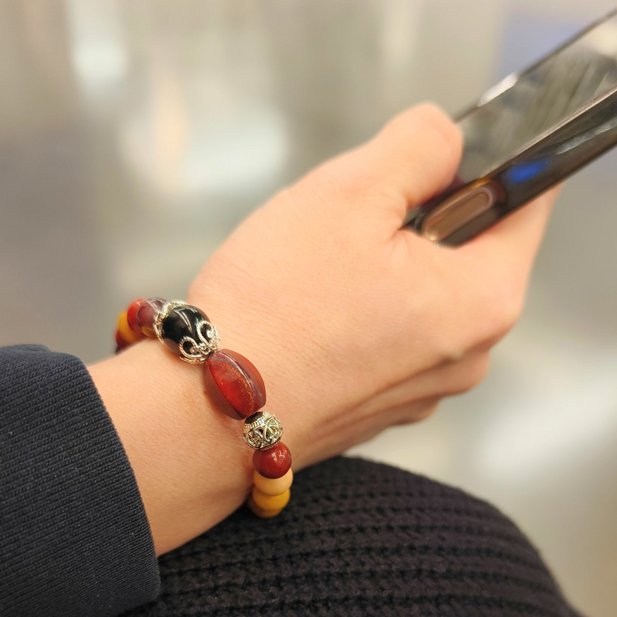 Elaris -  Healing bracelet-Red Jasper, Mookaite, Obsidian worn on wrist holding a phone