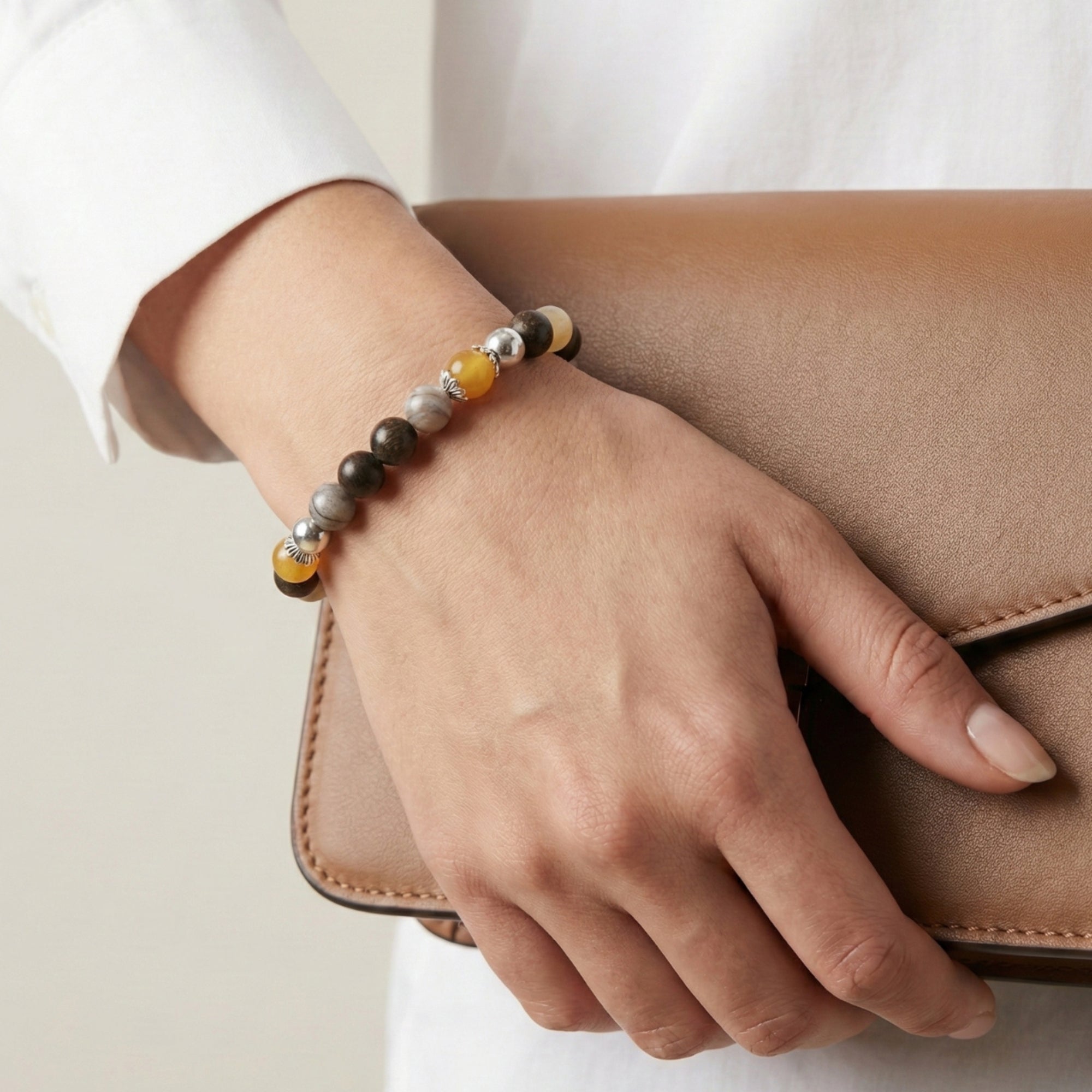 MARCEL Prosper Bracelet – Bronzite, Yellow Jade & Bamboo Leaf Agate with a lady worn on her wrist and holding a clutch bag
