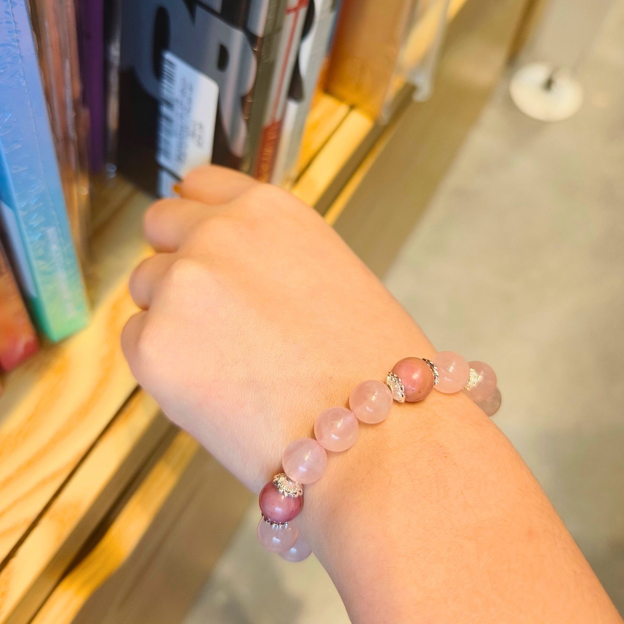 SEREN Rose Quartz & Rhodonite Bracelet worn on wrist in a book store